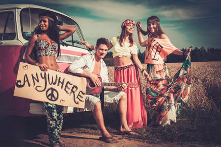 Multinational hippie hitchhikers with guitar and luggage on a roadの写真素材
