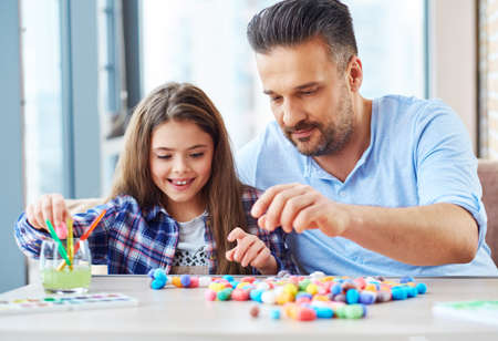 Beautiful little girl with her father playing with colored set for creativityの写真素材