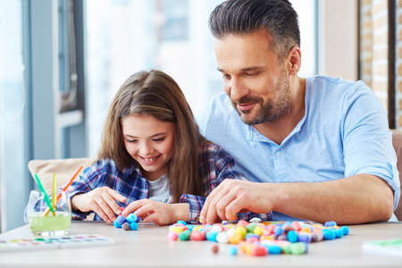 Beautiful little girl with her father playing with colored set for creativityの写真素材