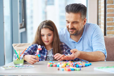 Beautiful little girl with her father playing with colored set for creativityの写真素材