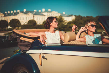 Two stylish ladies in a classic convertibleの写真素材