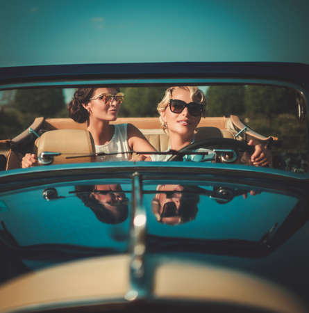 Two stylish ladies in a classic convertibleの写真素材