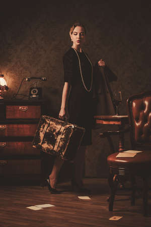 Beautiful woman with suitcase in retro interiorの写真素材