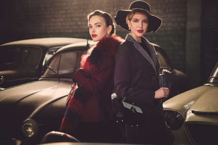 Two women among retro cars in garage