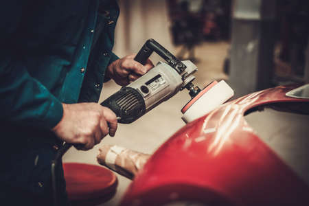 Mechanic polishing car body details in restoration workshop.の写真素材