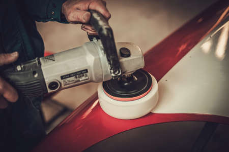 Mechanic polishing car body details in restoration workshop.の写真素材