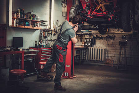 Mechanic working on classic car wheels and suspension in restoration workshop.の写真素材