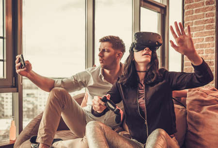 Cheerful couple having fun with VR in home interior.の写真素材