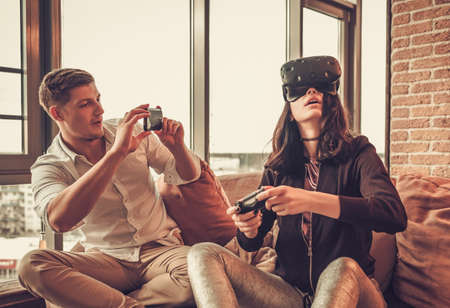 Cheerful couple having fun with VR in home interior.