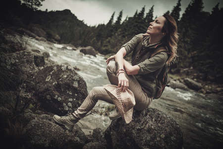 Beautiful woman hiker near wild mountain riverの写真素材