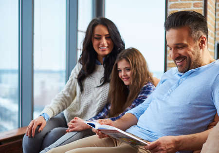 Father reading book to his cheerful family.の写真素材