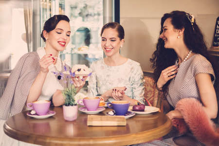 Three elegant young ladies in a cafeの写真素材