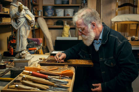 Senior wood carving professional during workの写真素材