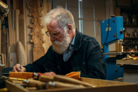 Senior wood carving professional during workの写真素材