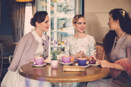 Three elegant young ladies in a cafeの写真素材