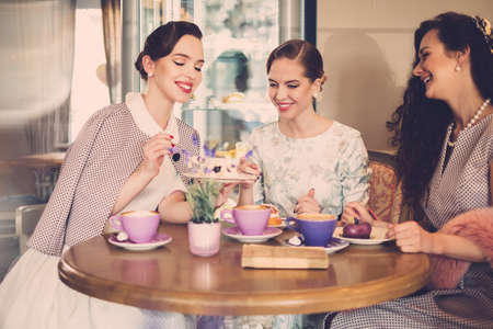 Three elegant young ladies in a cafeの写真素材