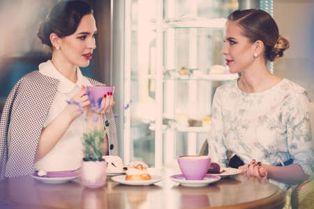 Two elegant young ladies in a cafeの写真素材