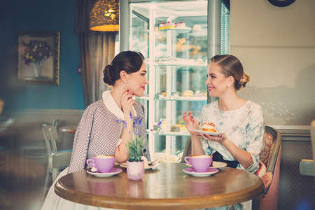 Two elegant young ladies in a cafeの写真素材