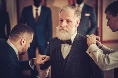 Tailor and his protege measuring client for custom made garment