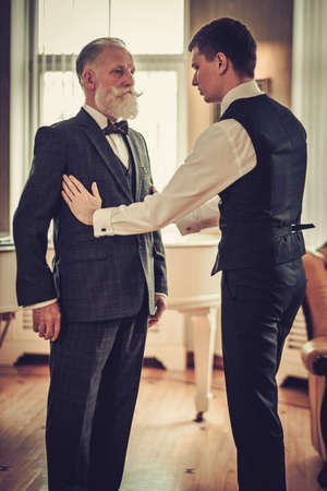 Tailors protege measuring client for custom made garmentの写真素材