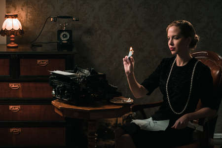 Beautiful woman burning letter in retro interiorの写真素材