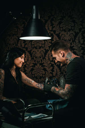 Professional tattoo artist makes a tattoo on a young girls handの写真素材