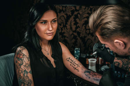 Professional tattoo artist makes a tattoo on a young girls handの写真素材