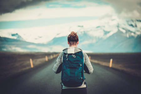 Travel hitchhiker woman walking on a roadの写真素材