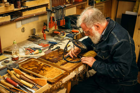 Senior wood carving professional during workの写真素材