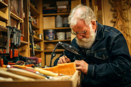Senior wood carving professional during workの写真素材