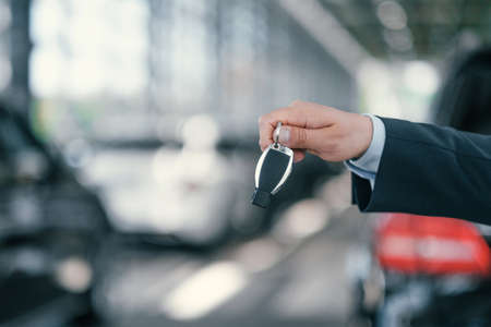 Giving a key from new car at dealership showroomの写真素材