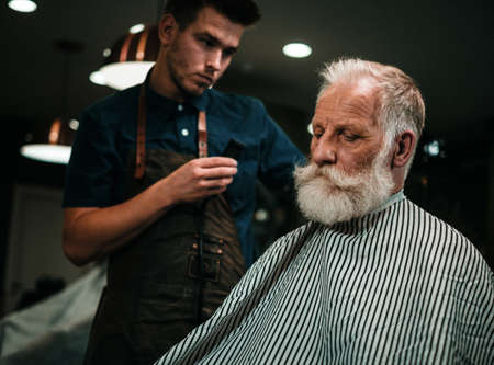Senior man visiting hairstylist in barber shop.の写真素材