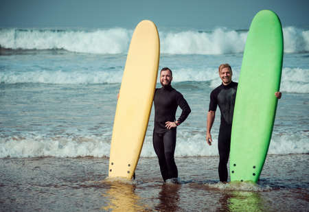 Surfer beginner and instructor on a beach with a surfboards