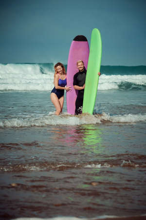 Surfer couple on the beach with a surfing boardの写真素材