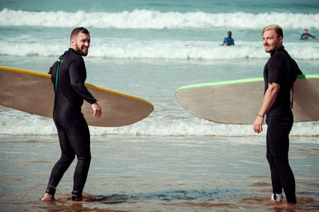 Surfer beginner and instructor on a beach with a surfing boardsの写真素材