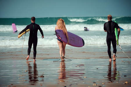 Surfer friends on a beach with a surfing boardsの写真素材