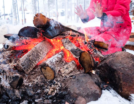 Woman near bonfire in winter landscape.の写真素材