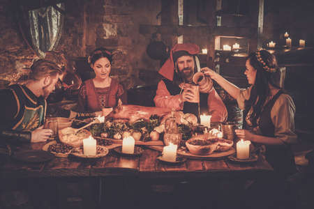 Medieval people eat and drink in ancient castle tavern.の写真素材