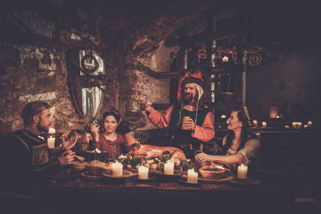 Medieval people eat and drink in ancient castle tavern.の写真素材