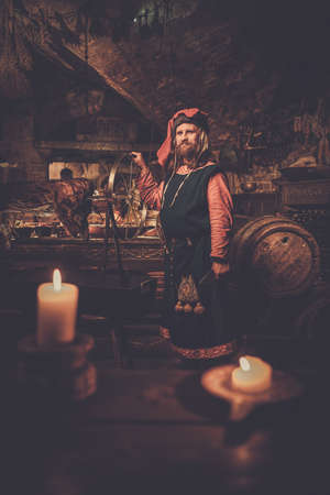 Medieval man doing roasted pig on the rack in ancient castle kitchen.の写真素材