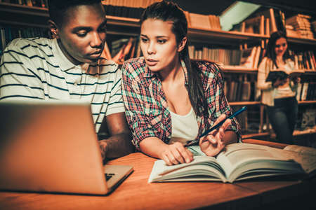 Multinational couple of students studying in the university library.