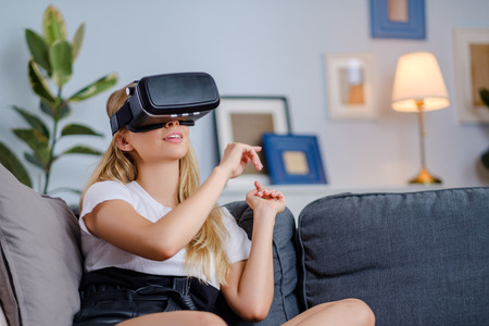 Attractive young woman in VR headset gesturing and smiling