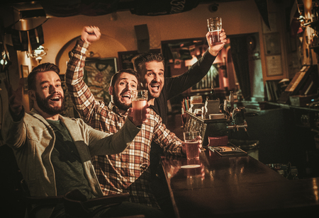 Old friends having fun and drinking draft beer at bar counter in pub.の写真素材