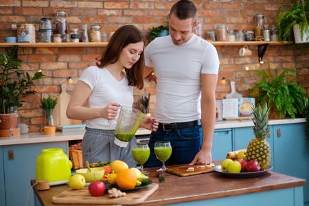 Young couple making smoothie in kitchenの写真素材