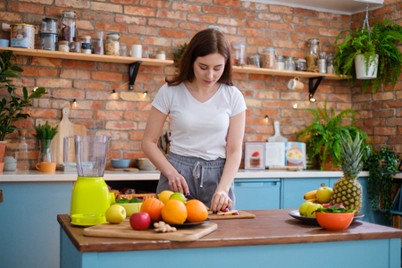 Young woman making smoothie in kitchenの写真素材