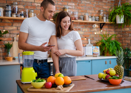 Young couple making smoothie in kitchenの写真素材