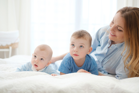 Happy middle aged mother with her children in a bedの写真素材