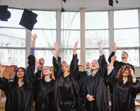Multi ethnic group of graduated students throwing hatsの写真素材