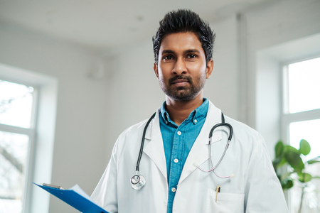 Indian doctor with stethoscope around neck in his officeの写真素材