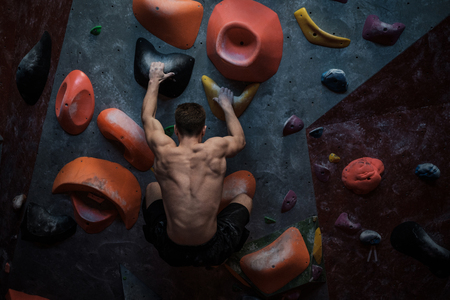 Athletic man practicing in a bouldering gymの写真素材